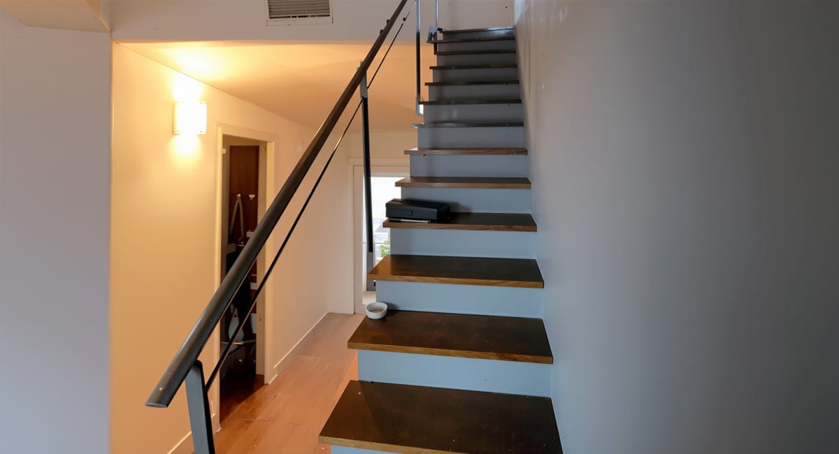 Escalier moderne en bois et métal dans un couloir lumineux d'une maison.