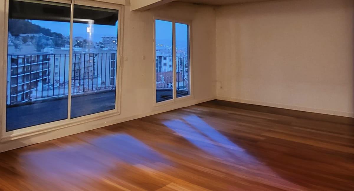 Pièce lumineuse d'un appartement avec vue sur la ville au crépuscule.