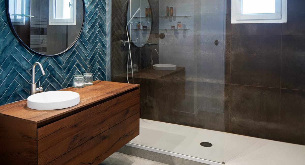 Salle de bain moderne avec carrelage bleu, meuble vasque en bois et douche à l'italienne.