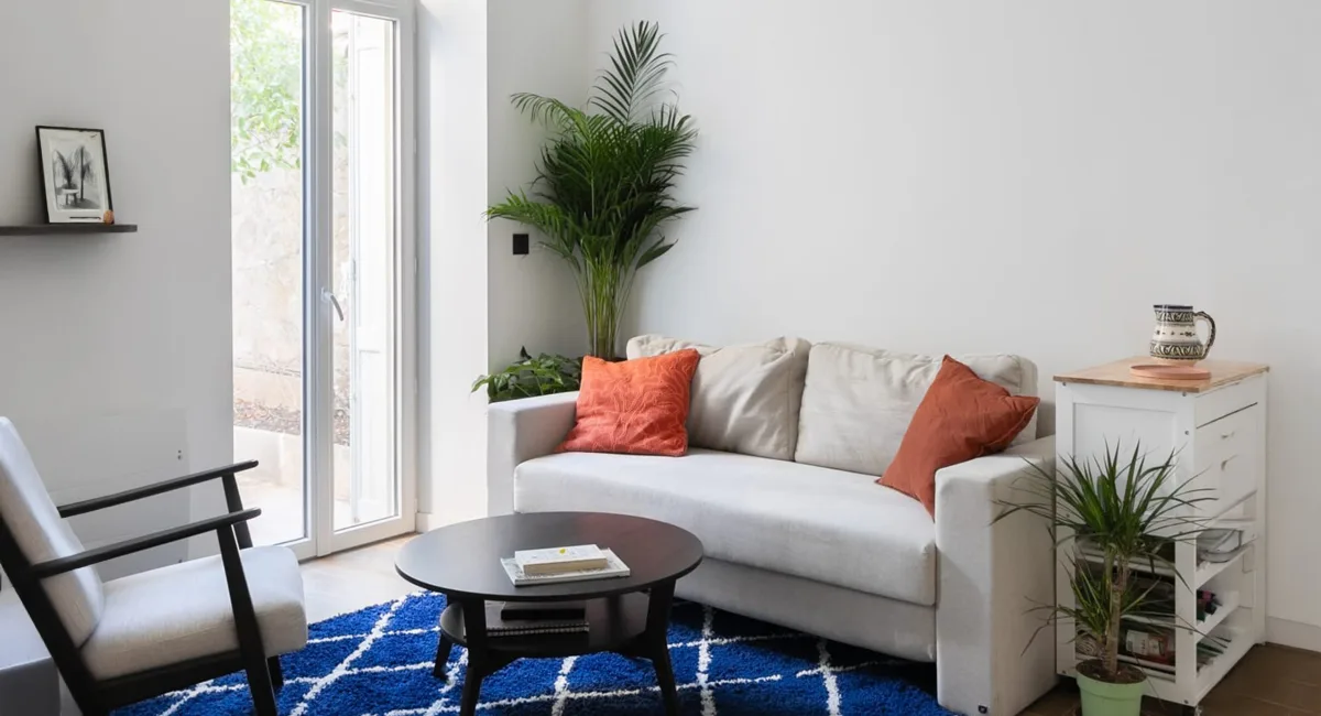 Un salon moderne et lumineux avec un canapé blanc et des coussins orange.