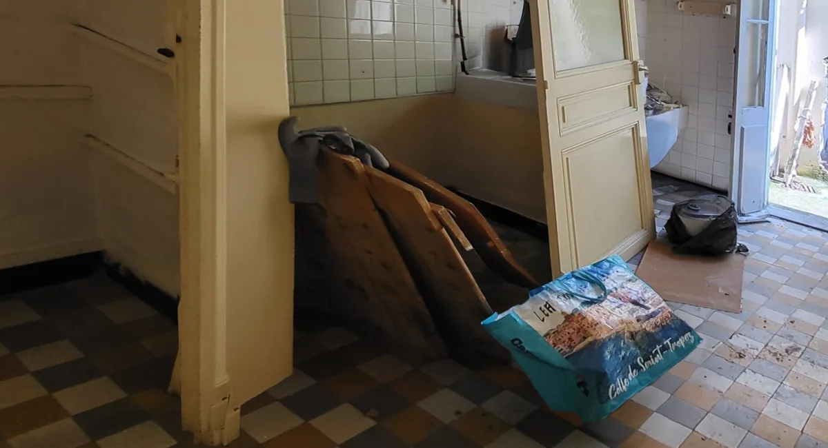 Une salle de bain en rénovation avec des planches de bois, un sac de sable et des meubles délabrés.