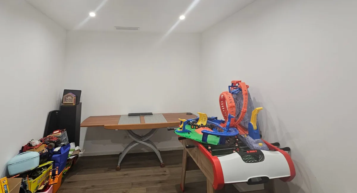 Une pièce blanche avec une table, des jouets et une piste de voitures.