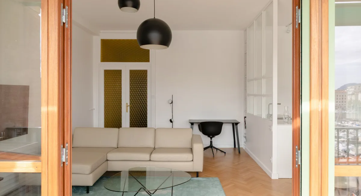 Intérieur d'un appartement moderne avec canapé et vue sur le port.