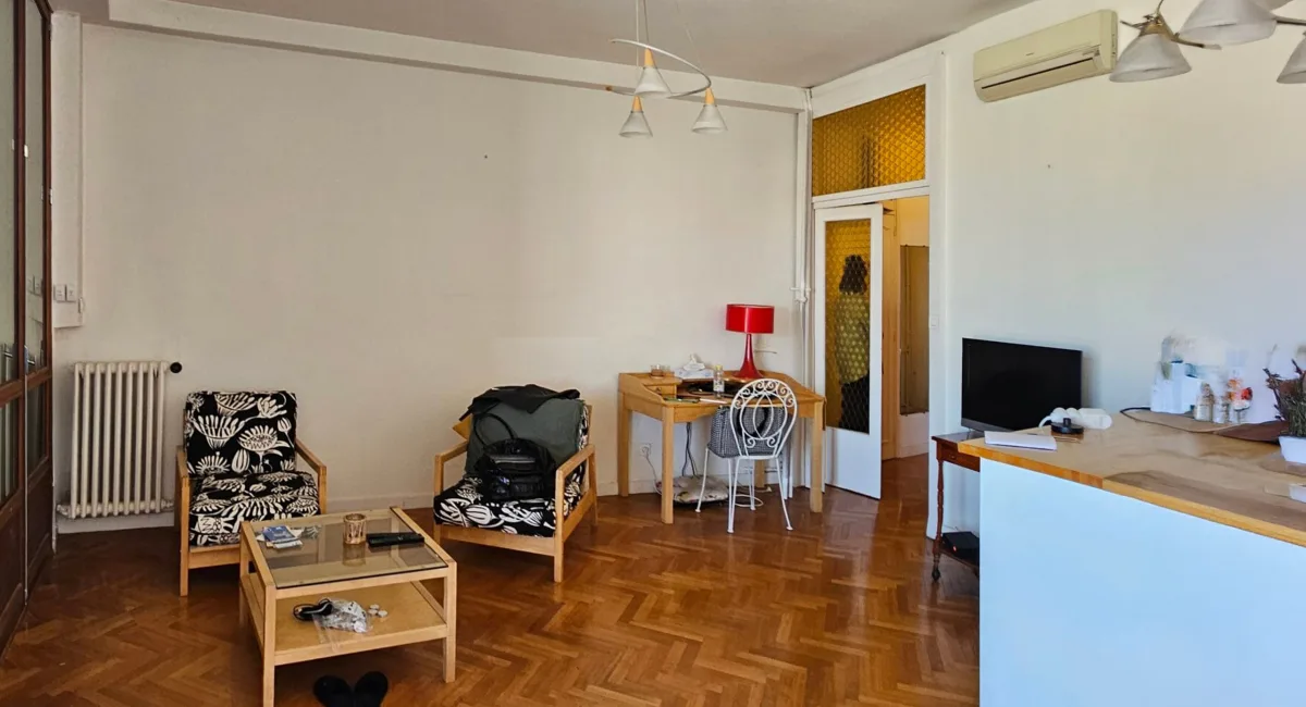 Intérieur d'un appartement simple avec canapé, table et radiateur.