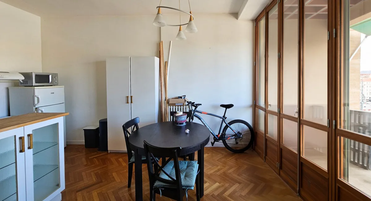 Intérieur d'un appartement avec une table, un vélo et des meubles bas.