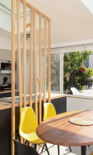 une table en bois surmontée de chaises à côté d'une fenêtre
